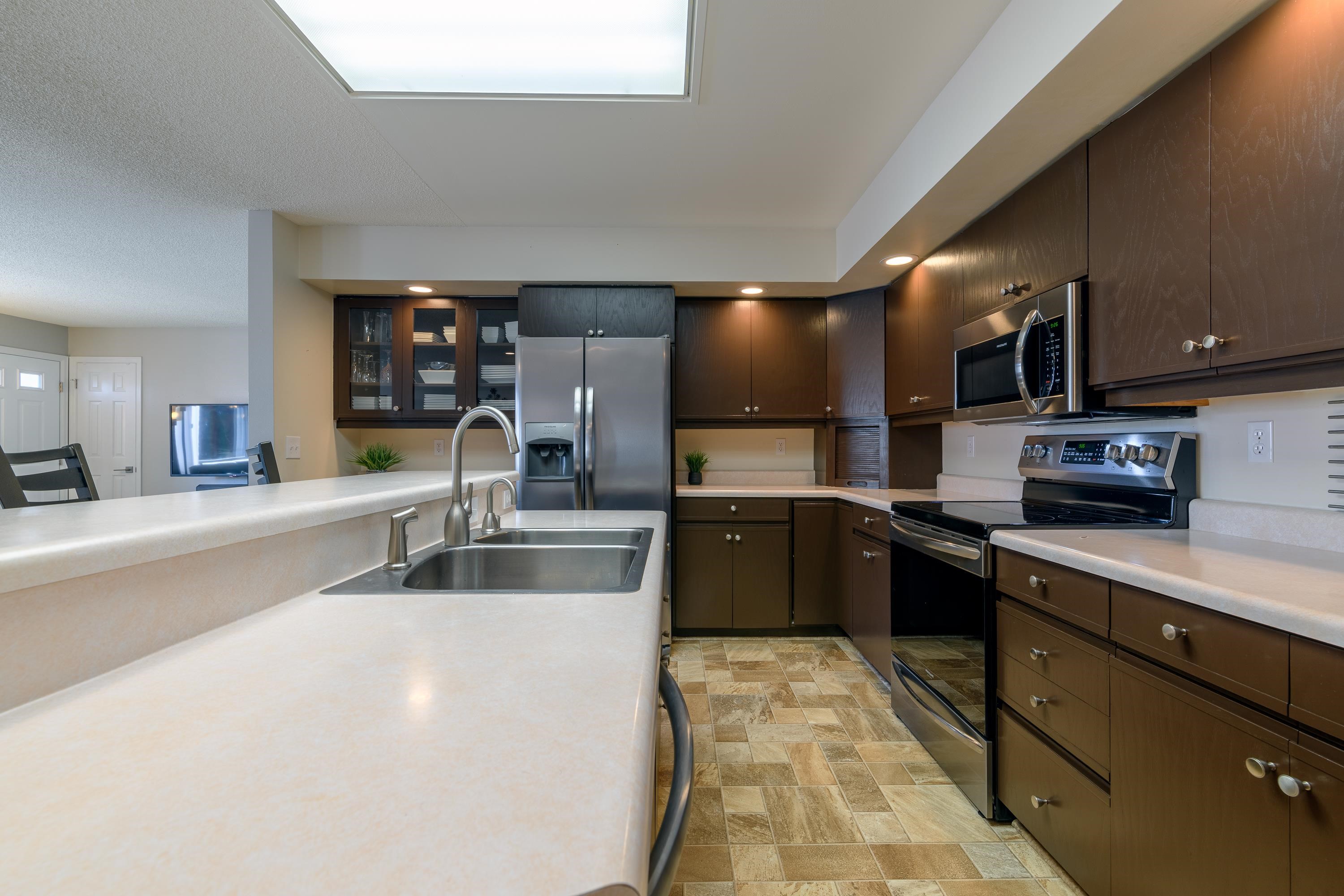 2700 G Road, Unit 5C Grand Junction, CO 81506 - Photo 11 of 25 a kitchen with stainless steel appliances a sink dishwasher a refrigerator microwave and stove with wooden floor