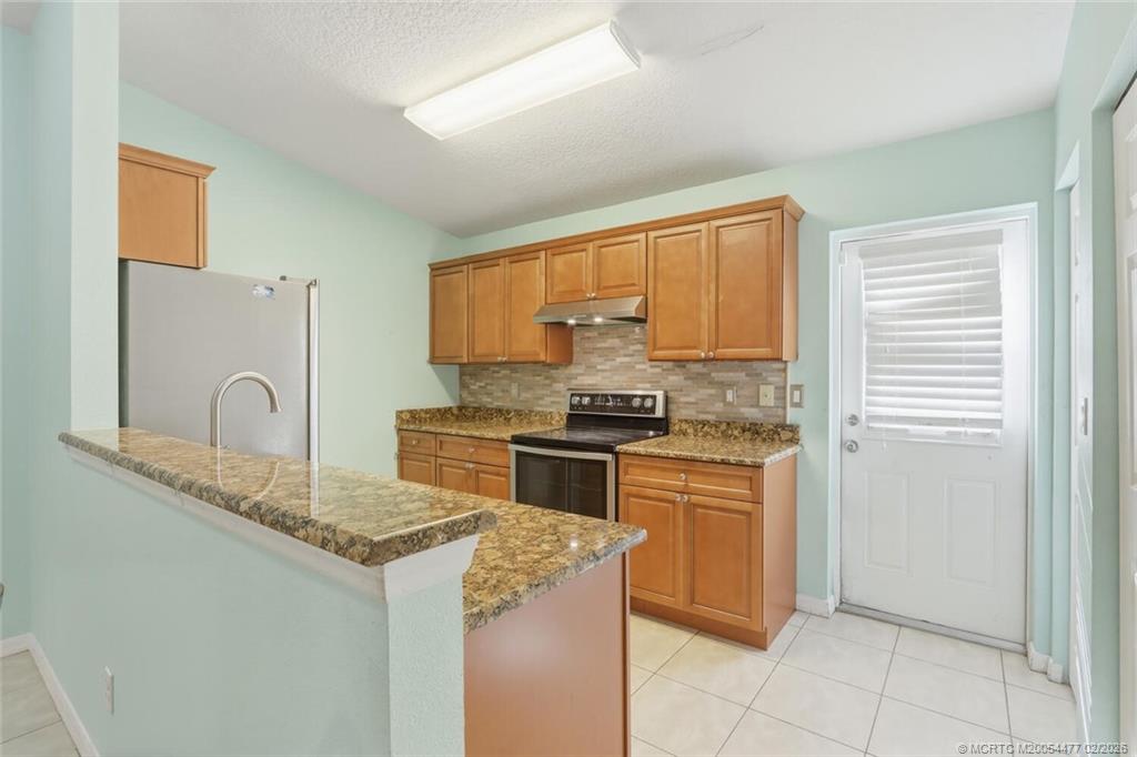 726 Southwest Bond Road Port St. Lucie, FL 34953 - Photo 12 of 31 a kitchen with granite countertop a stove top oven sink and cabinets