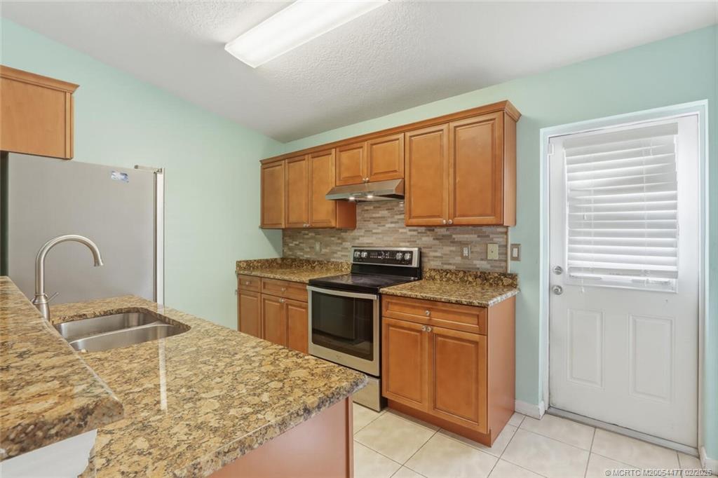 726 Southwest Bond Road Port St. Lucie, FL 34953 - Photo 13 of 31 a kitchen with kitchen island granite countertop a stove top oven microwave and cabinets