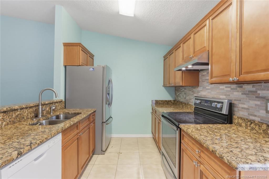 726 Southwest Bond Road Port St. Lucie, FL 34953 - Photo 14 of 31 a kitchen with stainless steel appliances granite countertop a sink stove and refrigerator