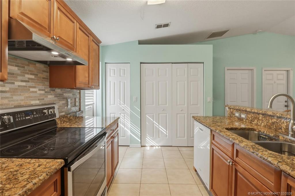 726 Southwest Bond Road Port St. Lucie, FL 34953 - Photo 16 of 31 a kitchen with stainless steel appliances granite countertop a sink stove and cabinets