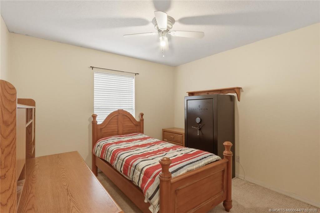 726 Southwest Bond Road Port St. Lucie, FL 34953 - Photo 23 of 31 a bedroom with a bed and a chandelier