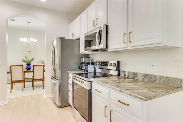a kitchen with stainless steel appliances granite countertop a refrigerator a stove and white cabinets