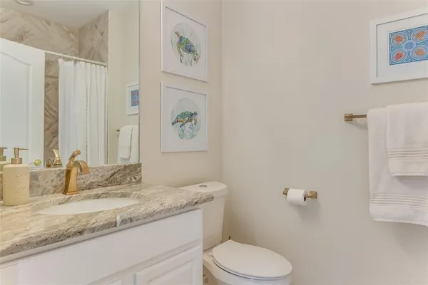 a bathroom with a granite countertop sink a toilet and a mirror