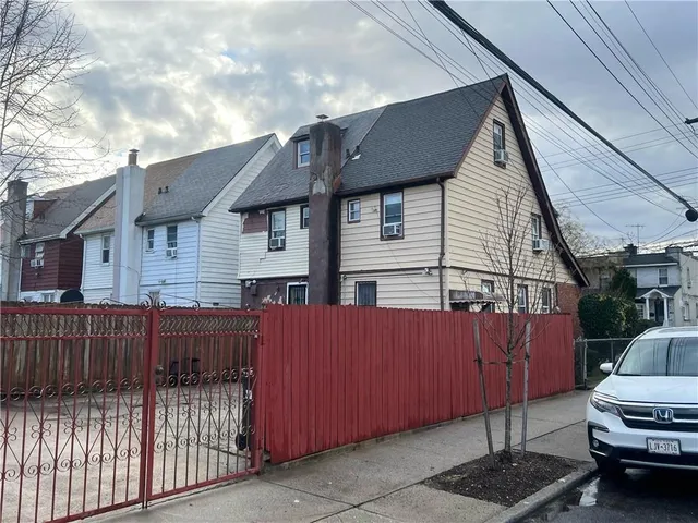 a view of a house with a small yard and wooden fence