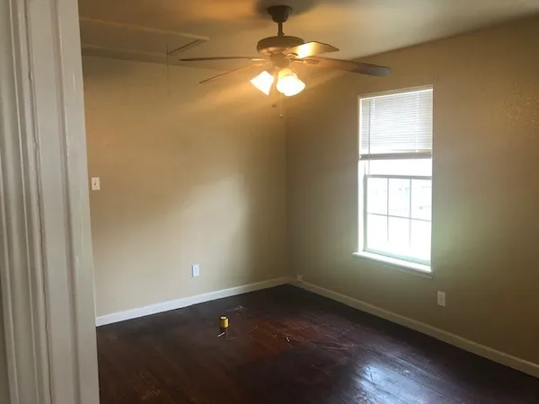 en empty room with windows and chandelier fan