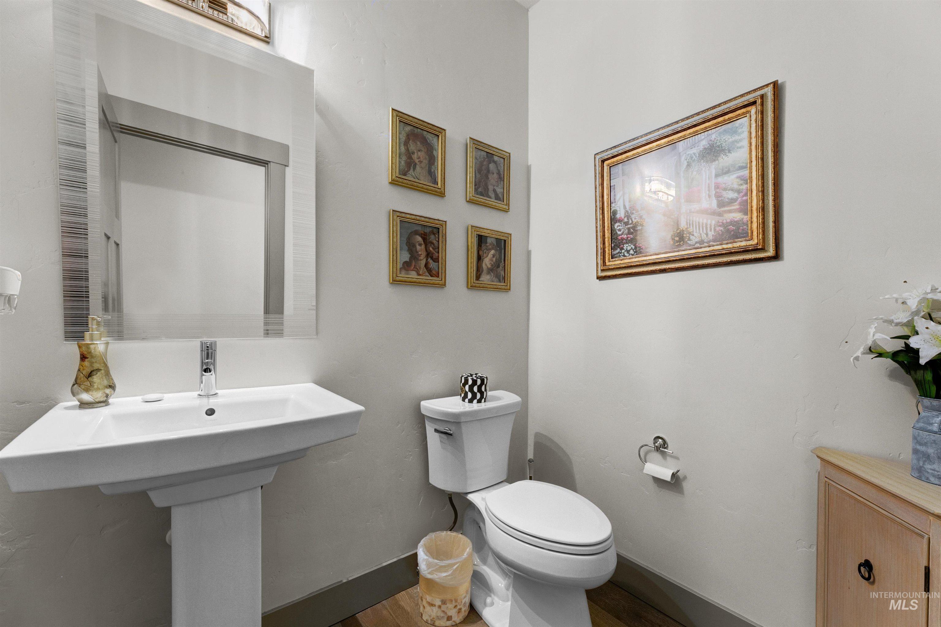 24398 Tombstone Ridge Court Middleton, ID 83644 - Photo 8 of 47 Pedestal sink with single-handle chrome faucet, rectangular wall mirror with frosted glass accents, wood-finish flooring, and light-toned wall paint