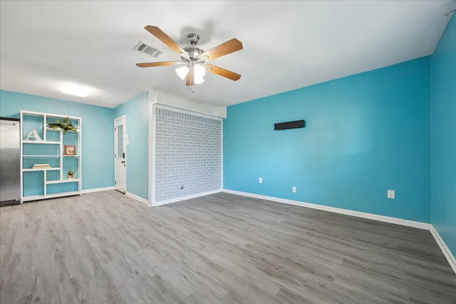 a view of an empty room with window and wooden floor