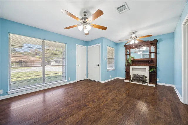 a view of an empty room with a window and wooden floor