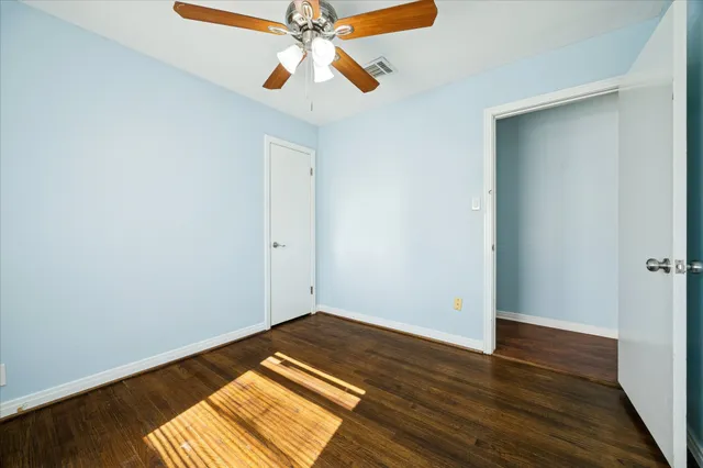 an empty room with wooden floor closet and fan chandelier fan