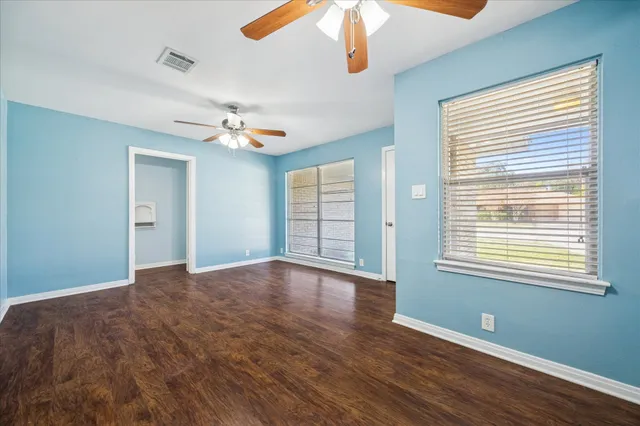 a view of an empty room with a window and wooden floor
