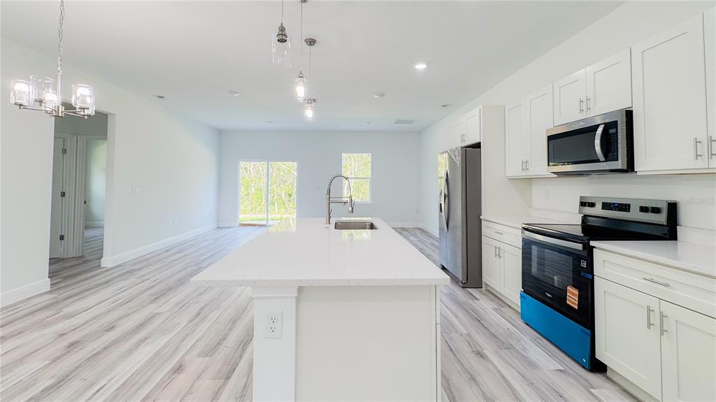 15625 Southwest 37th Circle Ocala, FL 34473 - Photo 11 of 27 a large kitchen with stainless steel appliances kitchen island granite countertop a refrigerator a stove top oven a sink dishwasher and white cabinets with wooden floor