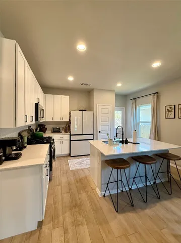a kitchen with stainless steel appliances kitchen island granite countertop a table chairs sink and cabinets