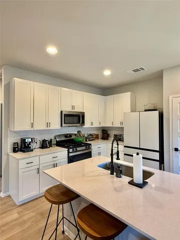 a kitchen with stainless steel appliances kitchen island granite countertop a stove a sink a refrigerator and cabinets