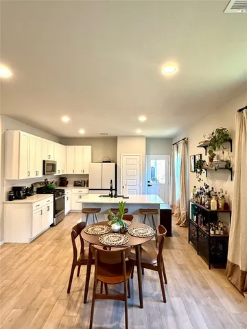 a dining hall with stainless steel appliances kitchen island granite countertop a dining table and chairs with wooden floor
