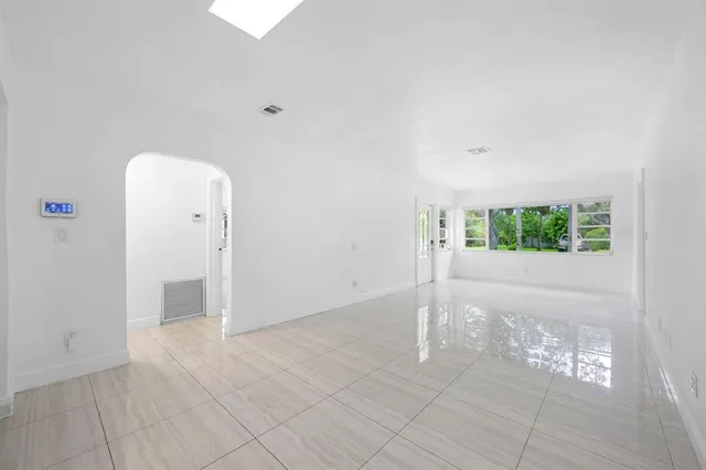 an empty room with kitchen view and a refrigerator