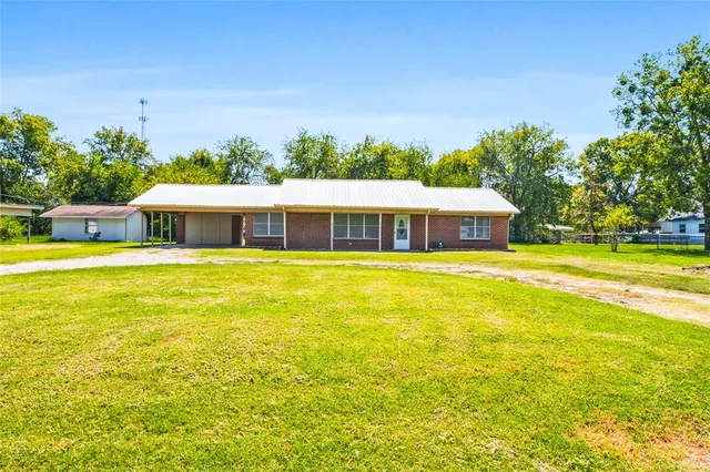 a view of a house with a big yard and large trees