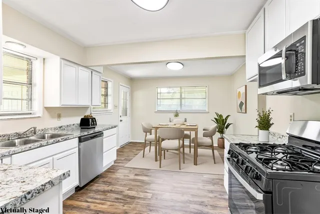 a kitchen with stainless steel appliances granite countertop a stove top oven a sink dishwasher a dining table and chairs with wooden floor