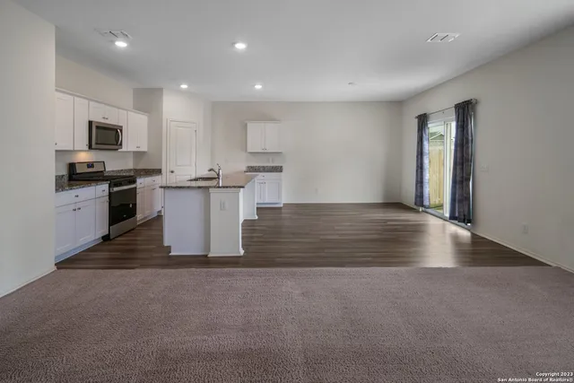 a view of kitchen with microwave stove refrigerator and cabinets