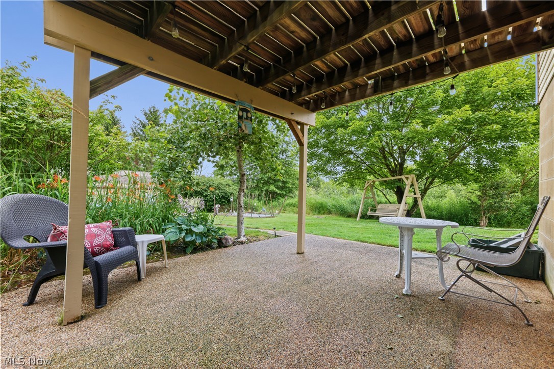 1835 Lynn Road Kent, OH 44240 - Photo 33 of 48 Under-deck patio featuring an exposed aggregate surface, overhead string lighting, and direct access to a landscaped garden area