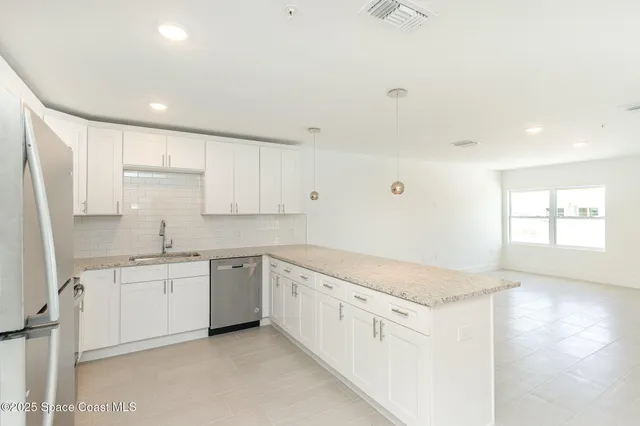 a kitchen with granite countertop a sink and white cabinets