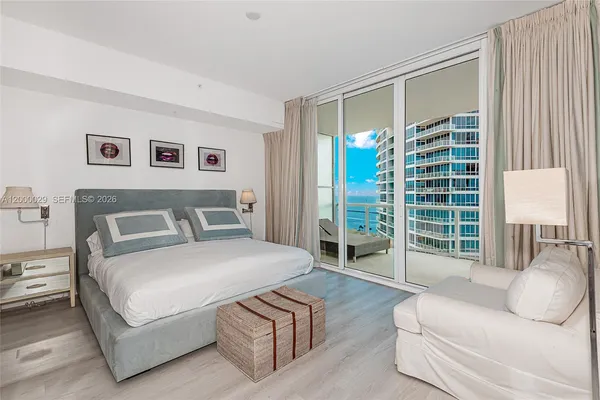 a spacious bedroom with a bed and glass window