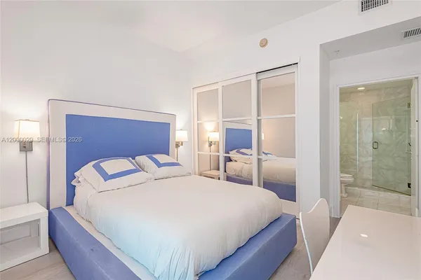 a bedroom with a bed and a large mirror with a wooden floor