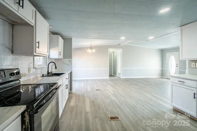 a view of an empty room with kitchen and a window