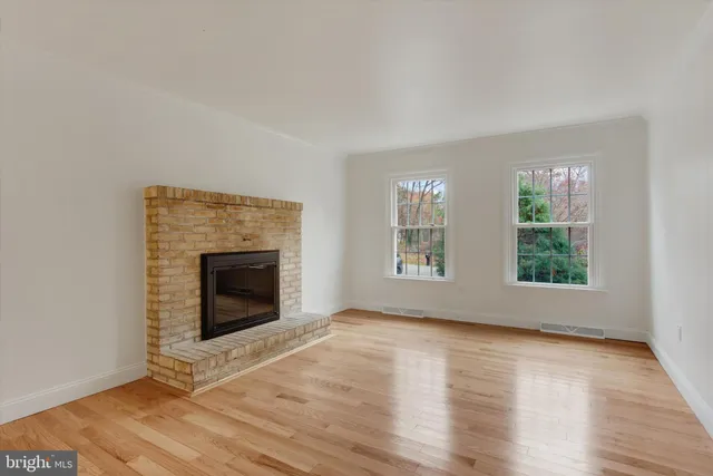 an empty room with windows and fireplace