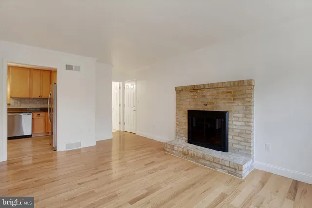 a view of an empty room with wooden floor and a fireplace