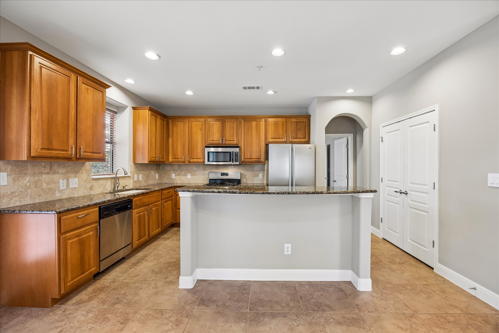 6705 Covered Bridge Drive, Unit 24 Austin, TX 78736 - Photo 10 of 31 a kitchen with stainless steel appliances granite countertop a refrigerator a sink dishwasher a stove and white cabinets with wooden floor