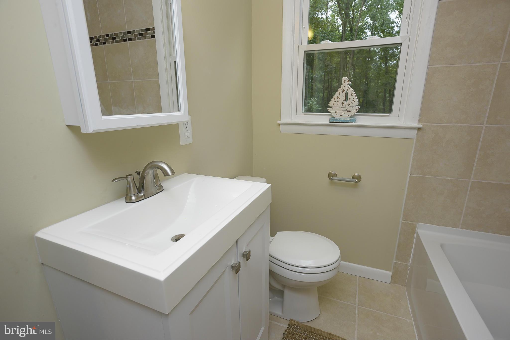 8413 Garland Road Pasadena, MD 21122 - Photo 18 of 30 a white toilet sitting next to a bathroom sink