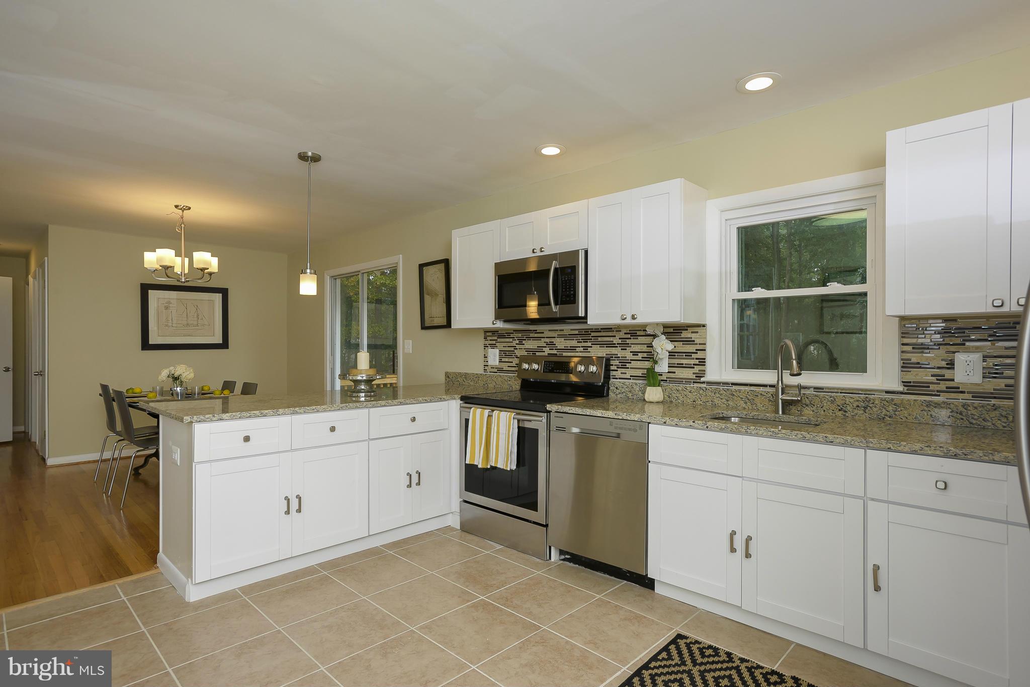 8413 Garland Road Pasadena, MD 21122 - Photo 10 of 30 a large white kitchen with a sink and dishwasher a stove top oven with wooden floor