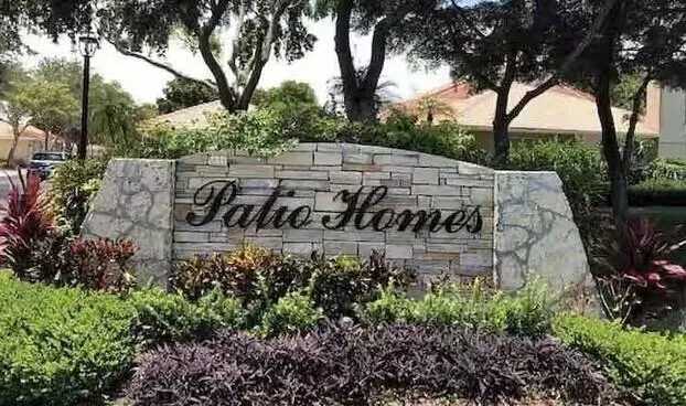 a view of a sign in a yard with tree in the background