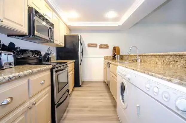 a kitchen with stainless steel appliances granite countertop a refrigerator a stove and a sink