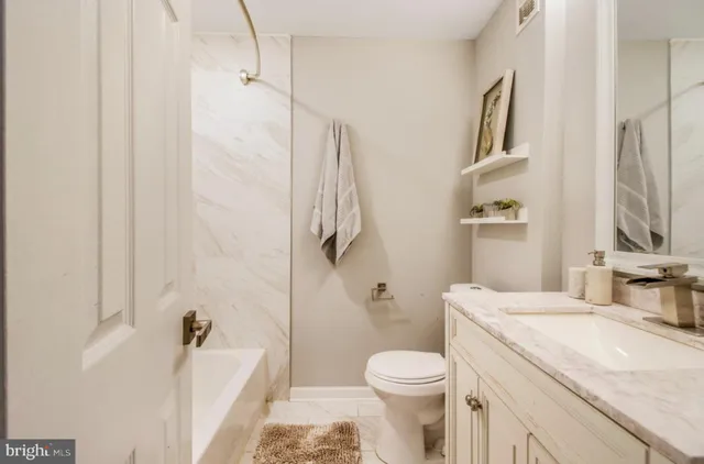 a bathroom with a granite countertop sink a toilet and a mirror
