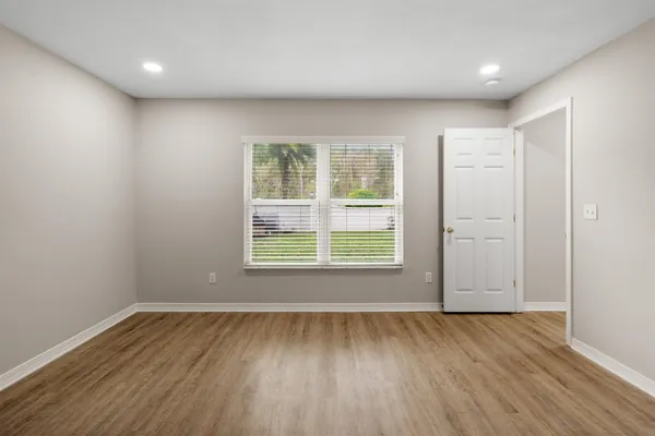 an empty room with wooden floor and windows