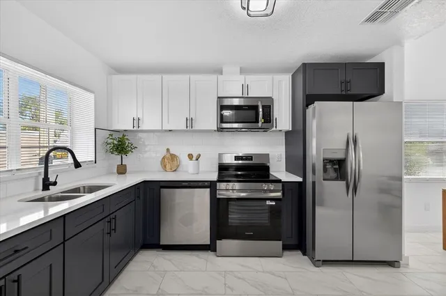 a kitchen with stainless steel appliances granite countertop a refrigerator a sink a stove a microwave and wooden cabinets