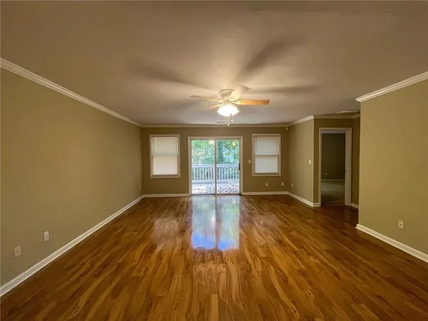 a view of an empty room with wooden floor and fan