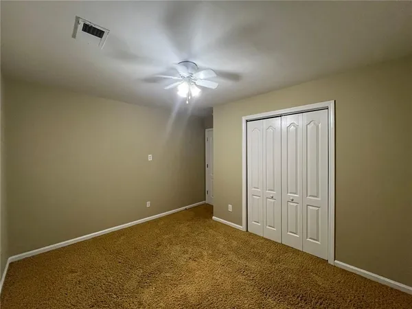 an empty room with chandelier fan and closet