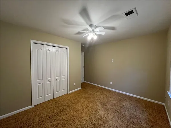 an empty room with closet and fan