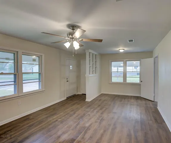 a view of an empty room with a window and wooden floor