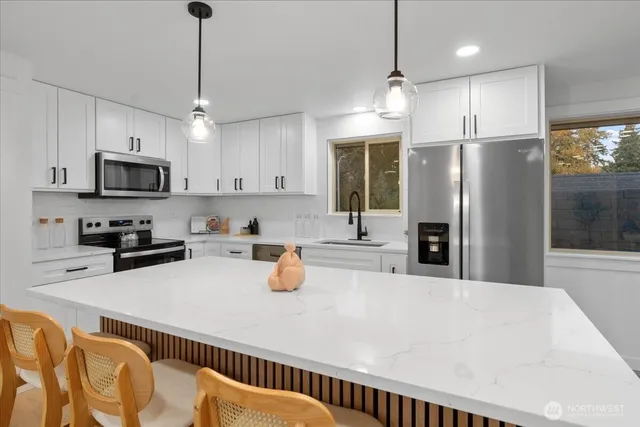 a kitchen with stainless steel appliances a refrigerator a sink a stove a microwave a center island and chairs