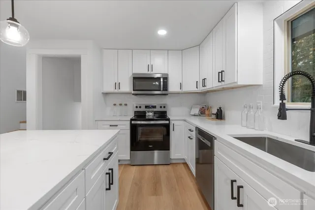 a kitchen with kitchen island a sink a stove oven and white cabinets