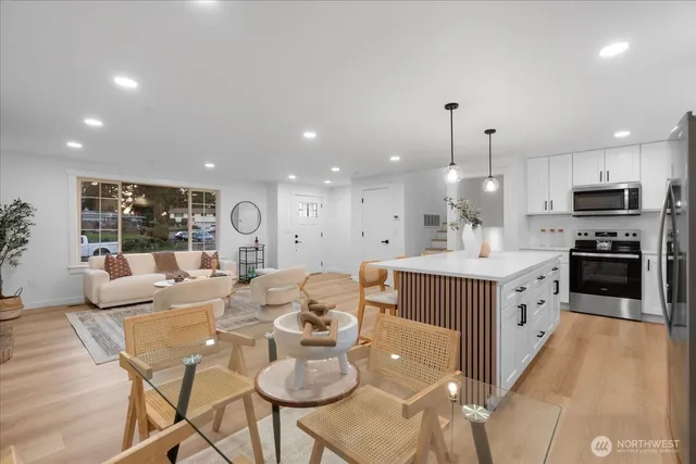 a large kitchen with kitchen island granite countertop lots of white cabinets appliances and a dining table