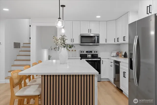 a kitchen with kitchen island a counter space a sink appliances and cabinets