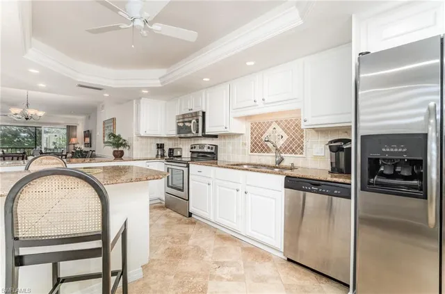 a kitchen with stainless steel appliances granite countertop a stove a sink a refrigerator and white cabinets