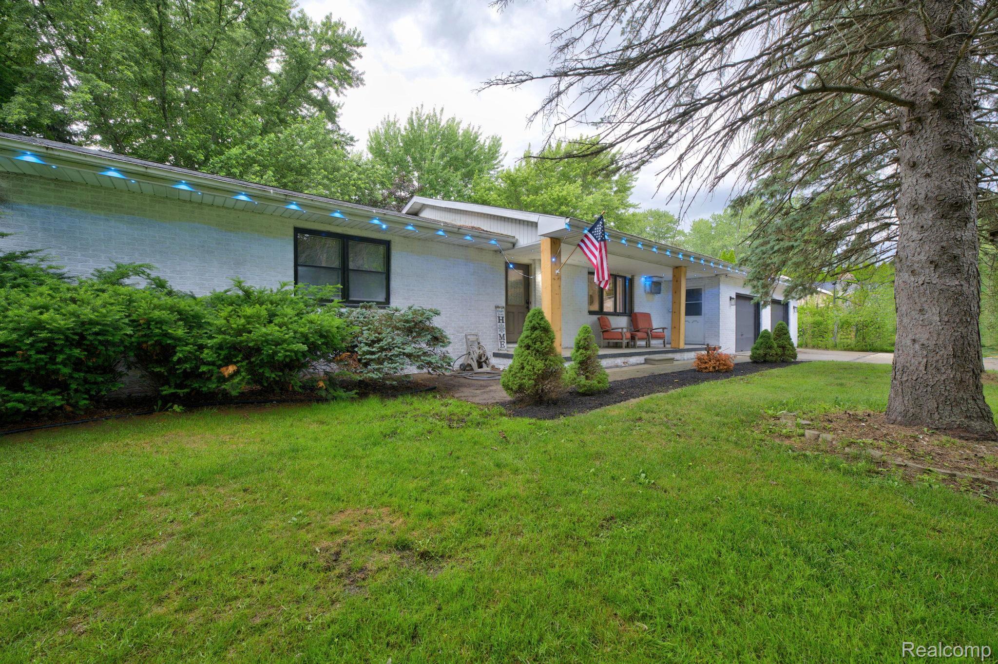 5330 Sheridan Road Saginaw, MI 48601 - Photo 3 of 50 White brick exterior with a covered porch featuring wood columns, a black framed window, and foundation plantings