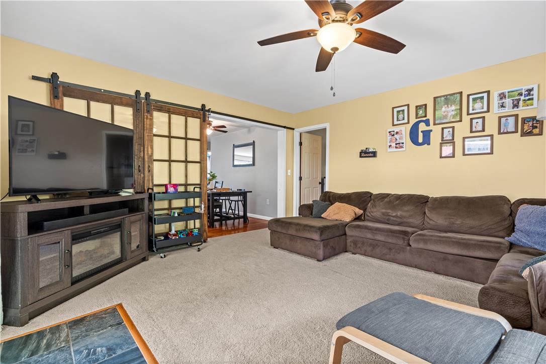 50 Kohls Road Northampton, PA 18067 - Photo 16 of 54 A welcoming living space features plush carpeting, a cozy electric fireplace, and practical barn doors, offering comfort and charm.
