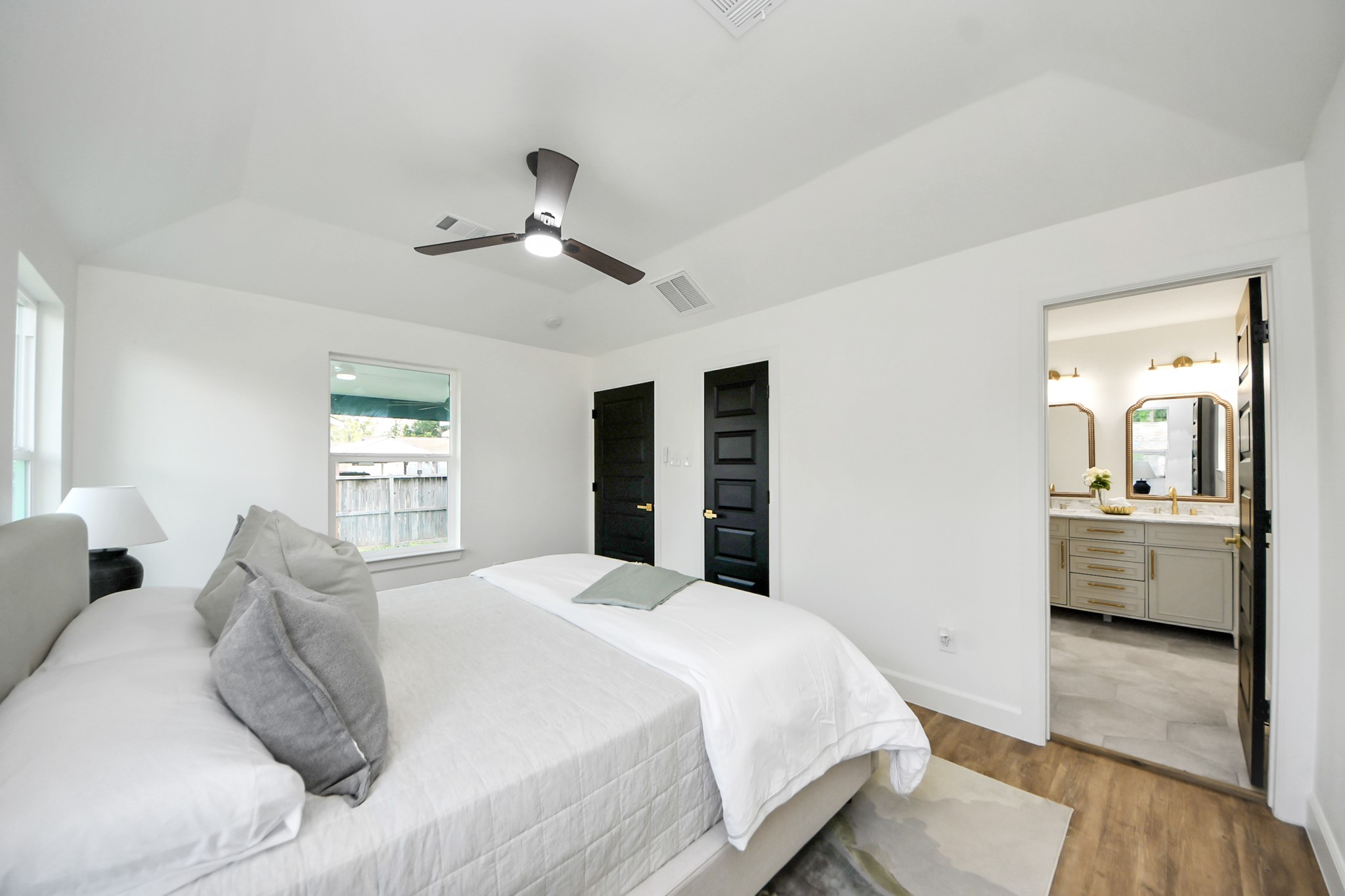 1737 Tabor Street Houston, TX 77009 - Photo 21 of 44 A serene, sunlit bedroom with vaulted ceilings that create an airy, restful retreat. Large windows invite in natural light, while neutral tones, a cozy bed, and simple, stylish touches complete the calm and inviting atmosphere.